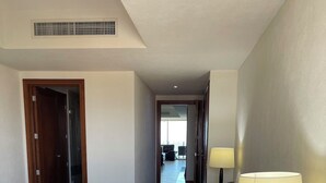 Ein Hotelzimmer mit einem großen Bett, einem Nachttisch mit Lampe, einer Tür und Blick auf den Balkon.