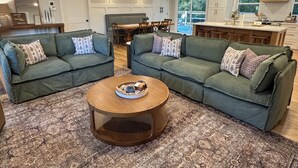 A living room with two green sofas, a wooden coffee table, and a patterned rug.