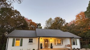 A single-story house with a front porch, a door, and a small front yard.