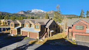 Une rangée de maisons de plain-pied, dotées de garages attenants, située dans un quartier résidentiel avec une chaîne de montagnes en arrière-plan.