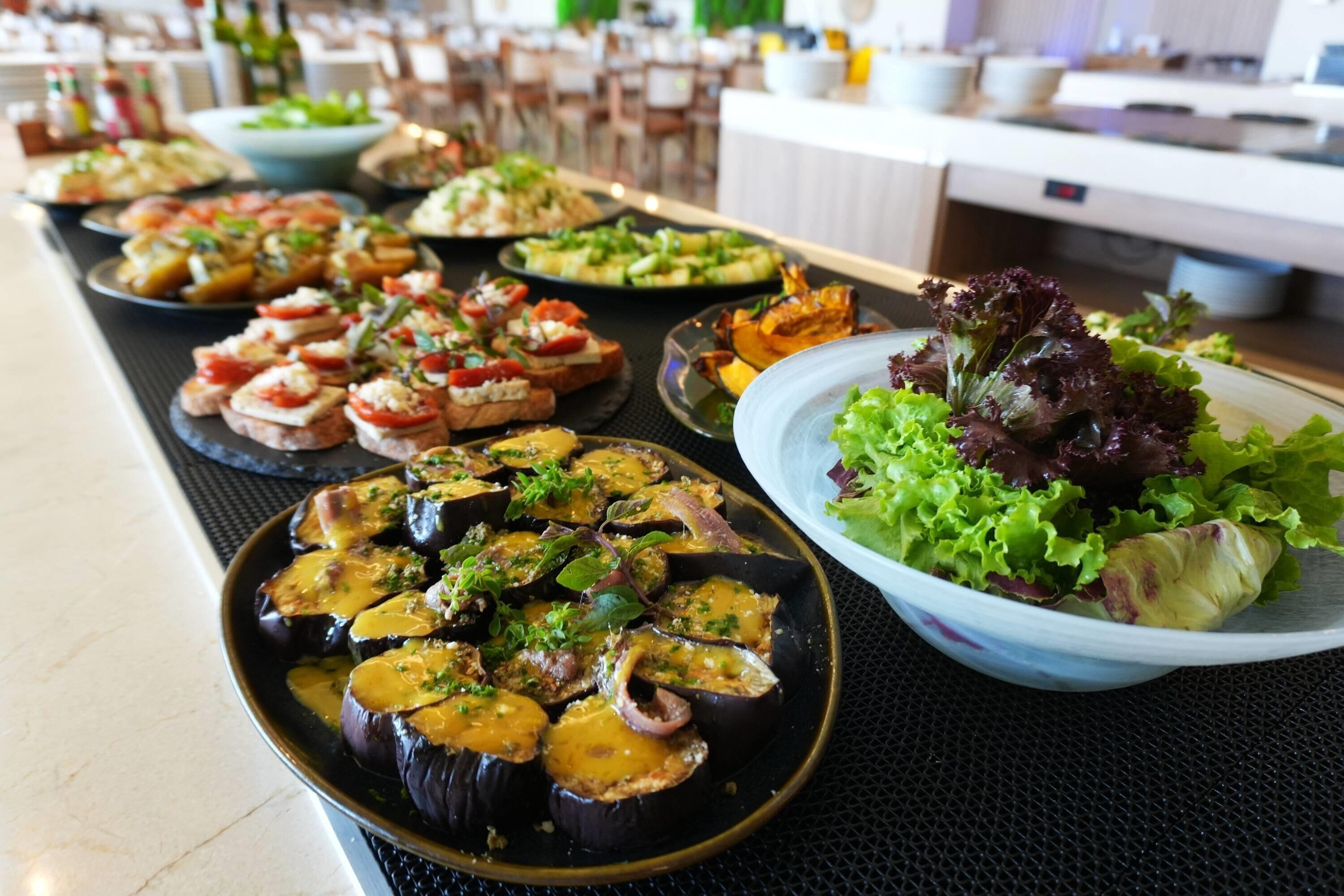 Ein Buffet mit verschiedenen Speisen, darunter Auberginen und Salat.