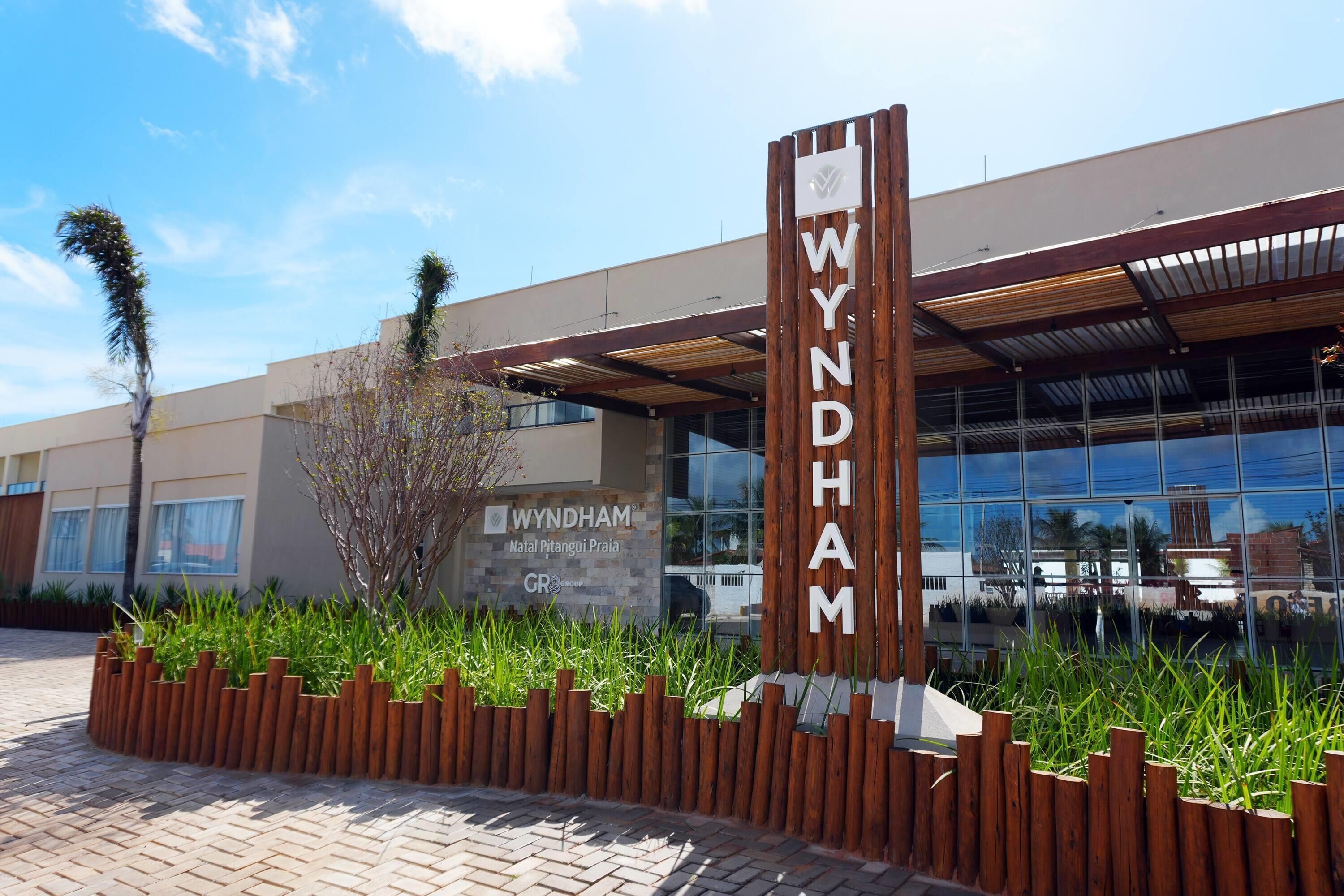 Um edifício com uma placa indicando 'WYNDHAM' e uma placa de identificação 'Natal Pitangui Praia'.