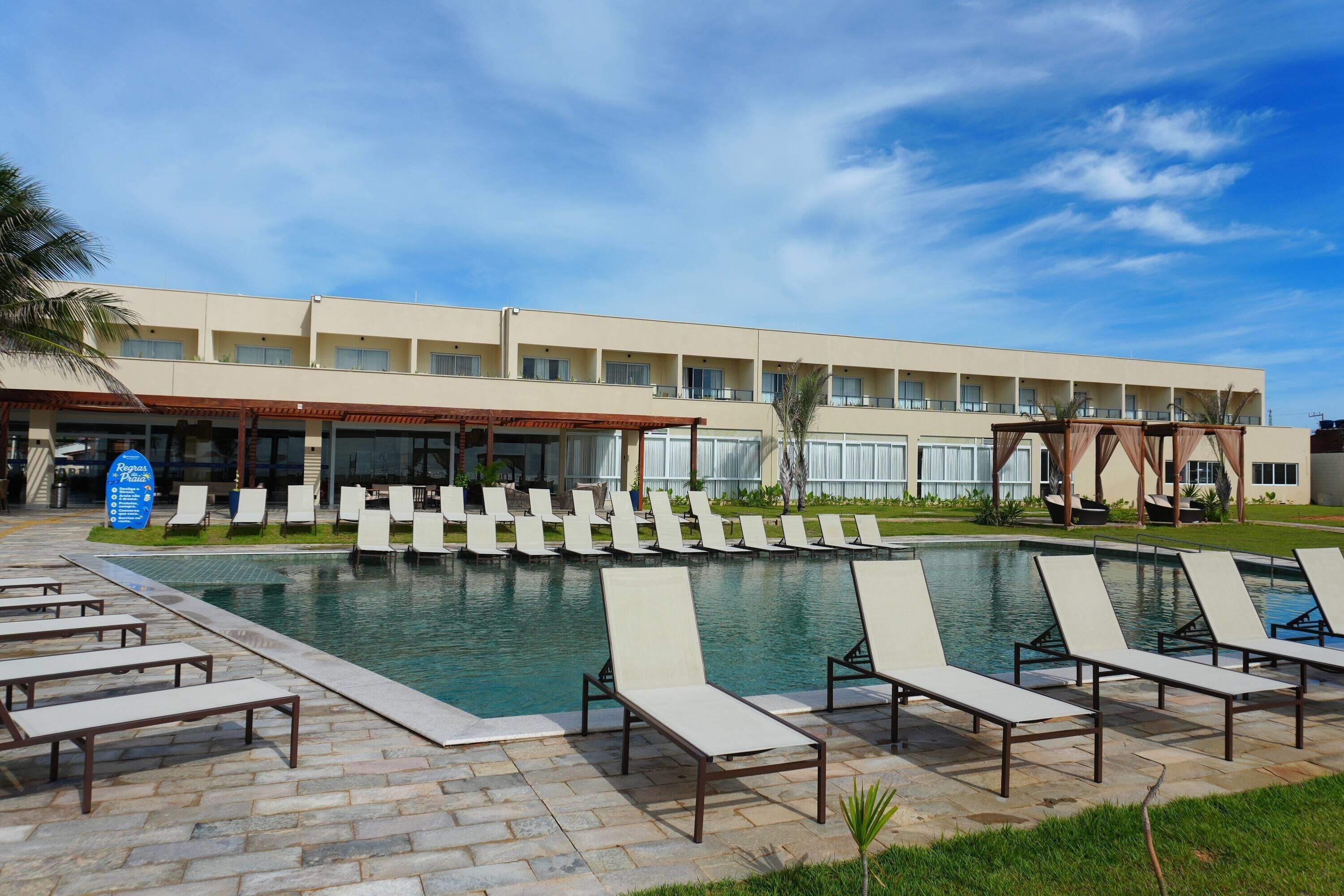 Ein Hotel mit Schwimmbad, Liegestühlen und einer überdachten Terrasse.