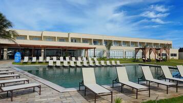 Ein Hotel mit Schwimmbad, Liegestühlen und einer überdachten Terrasse.