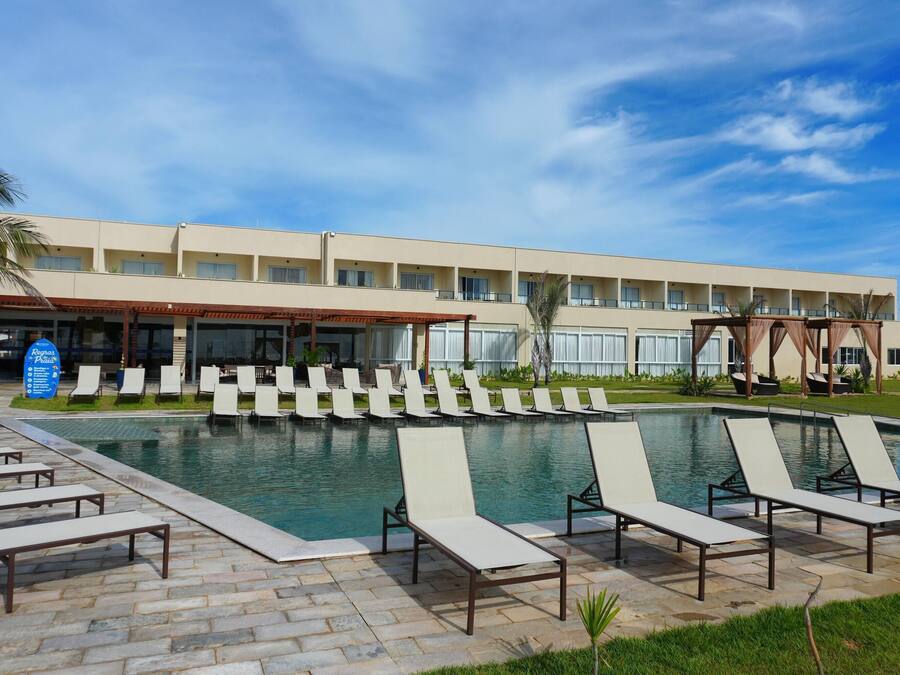 Ein Hotel mit Schwimmbad, Liegestühlen und einer überdachten Terrasse.