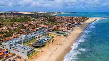 Na praia, areia branca, espreguiçadeiras, guarda-sóis