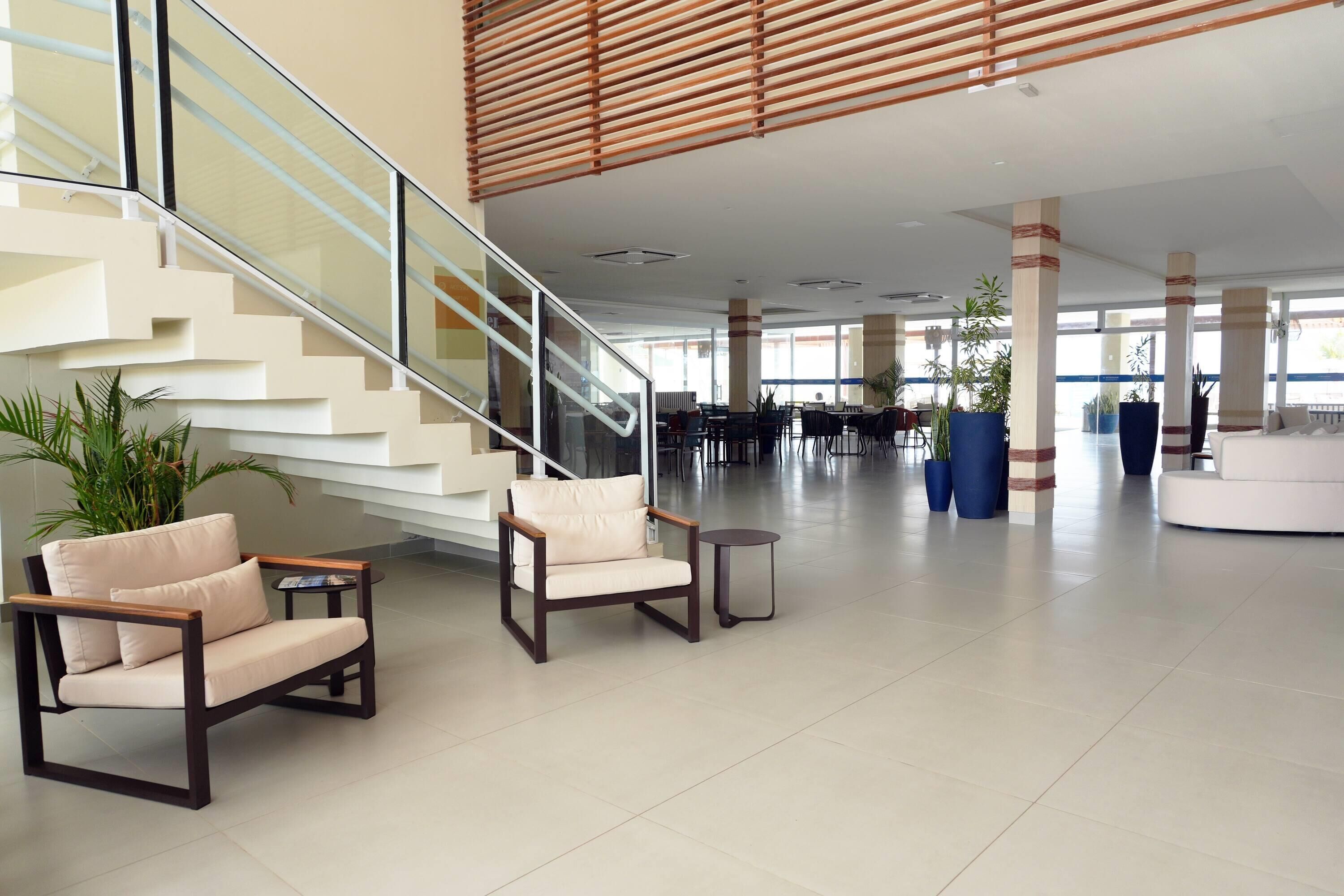 A spacious lobby with a staircase, seating area, and large windows.