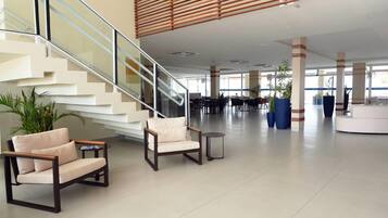 A spacious lobby with a staircase, seating area, and large windows.