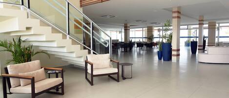 A spacious lobby with a staircase, seating area, and large windows.