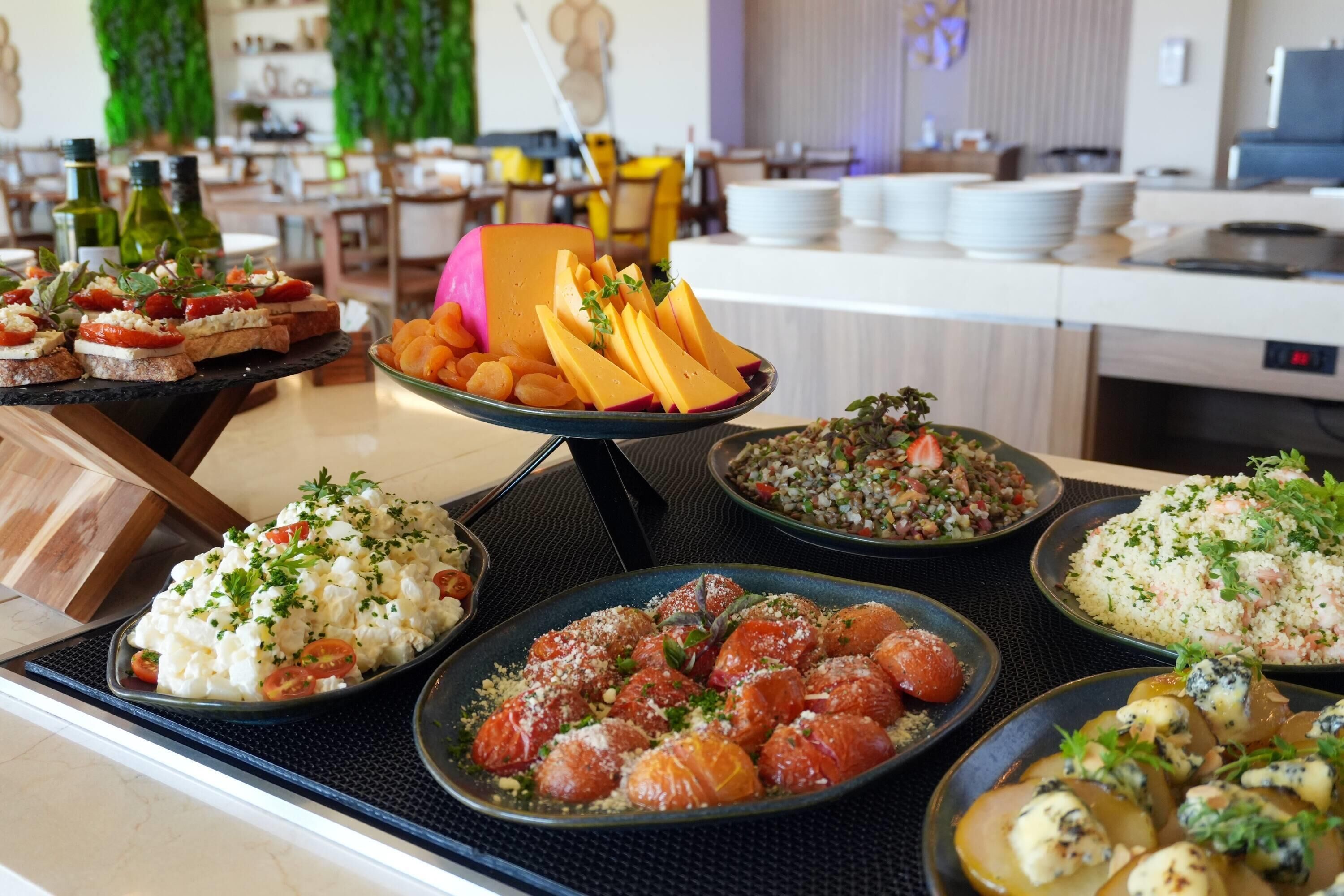 Un bufé con diversos platos, incluyendo queso, frutas y ensaladas.