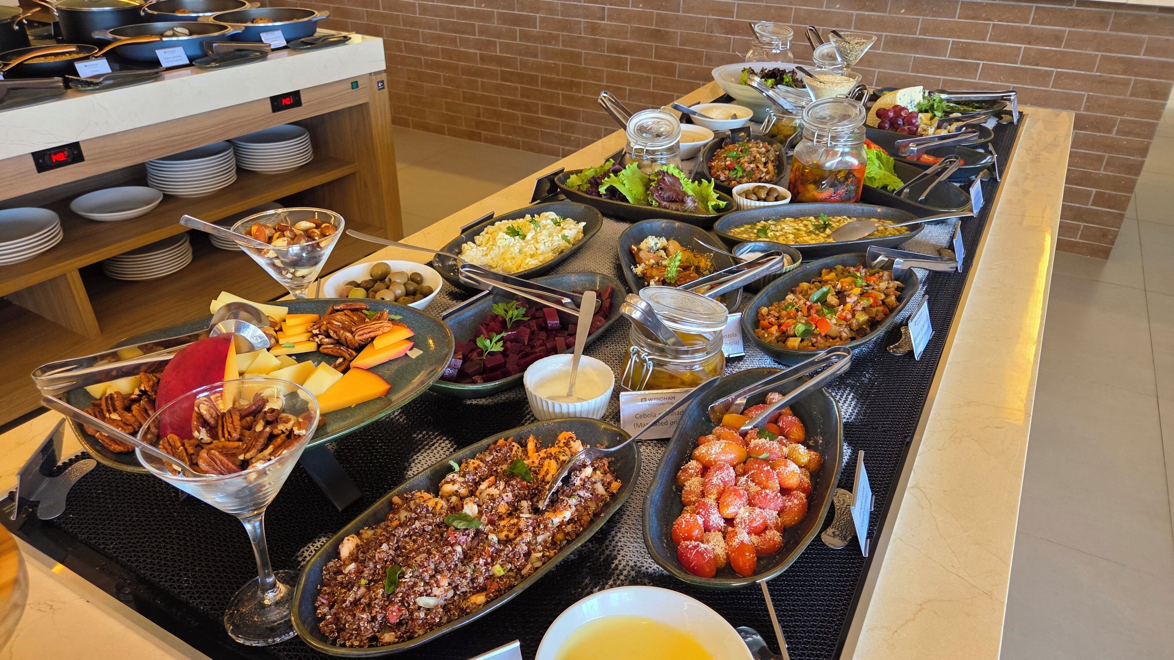 A buffet with various dishes including quinoa salad, roasted vegetables, and a selection of cheeses.