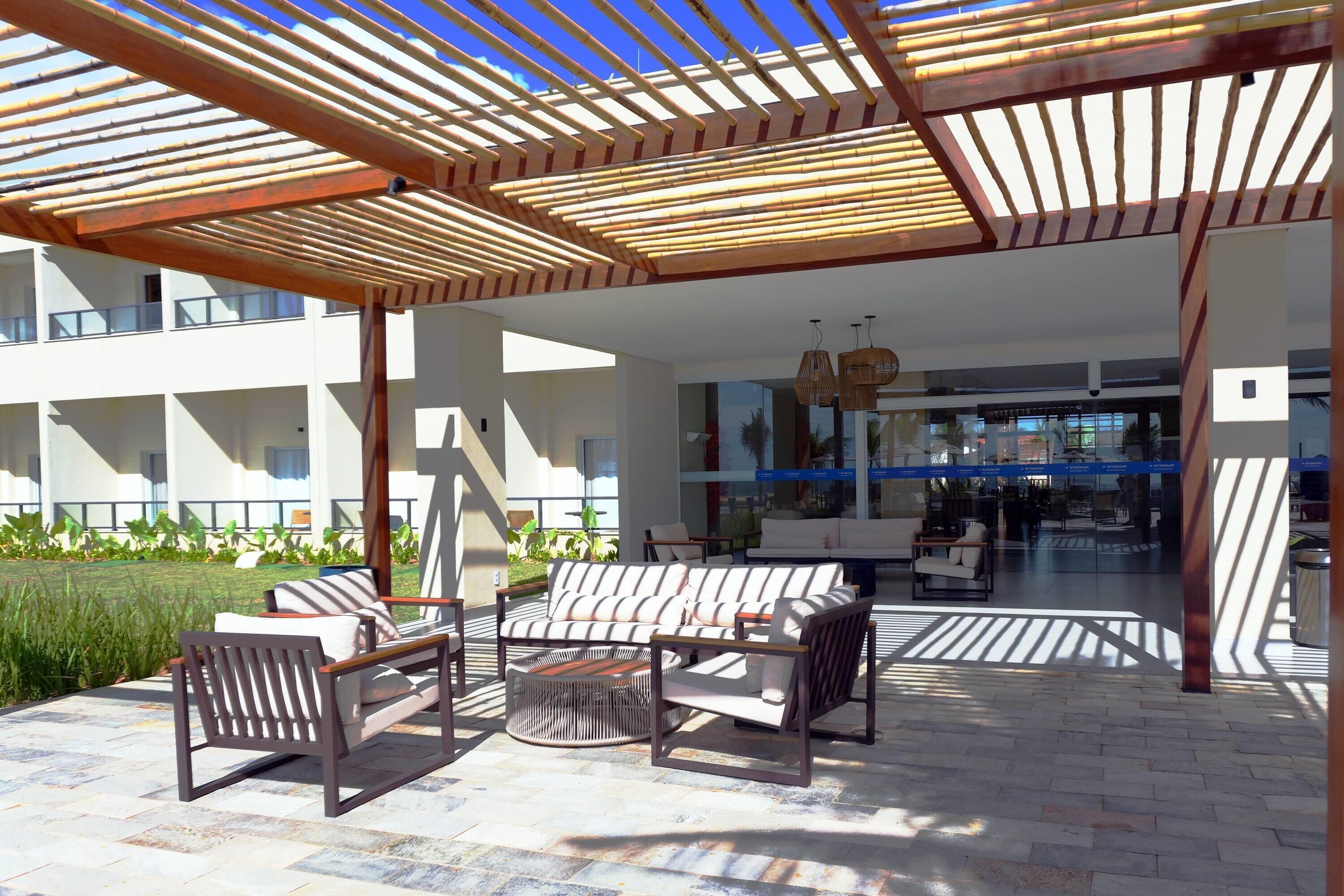 Un área de estar al aire libre con una pérgola de madera, una mesa redonda y varias sillas.