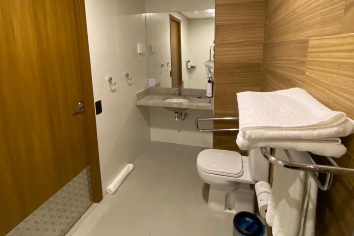 A modern bathroom with a wooden vanity, a toilet, a sink, and a mirror.