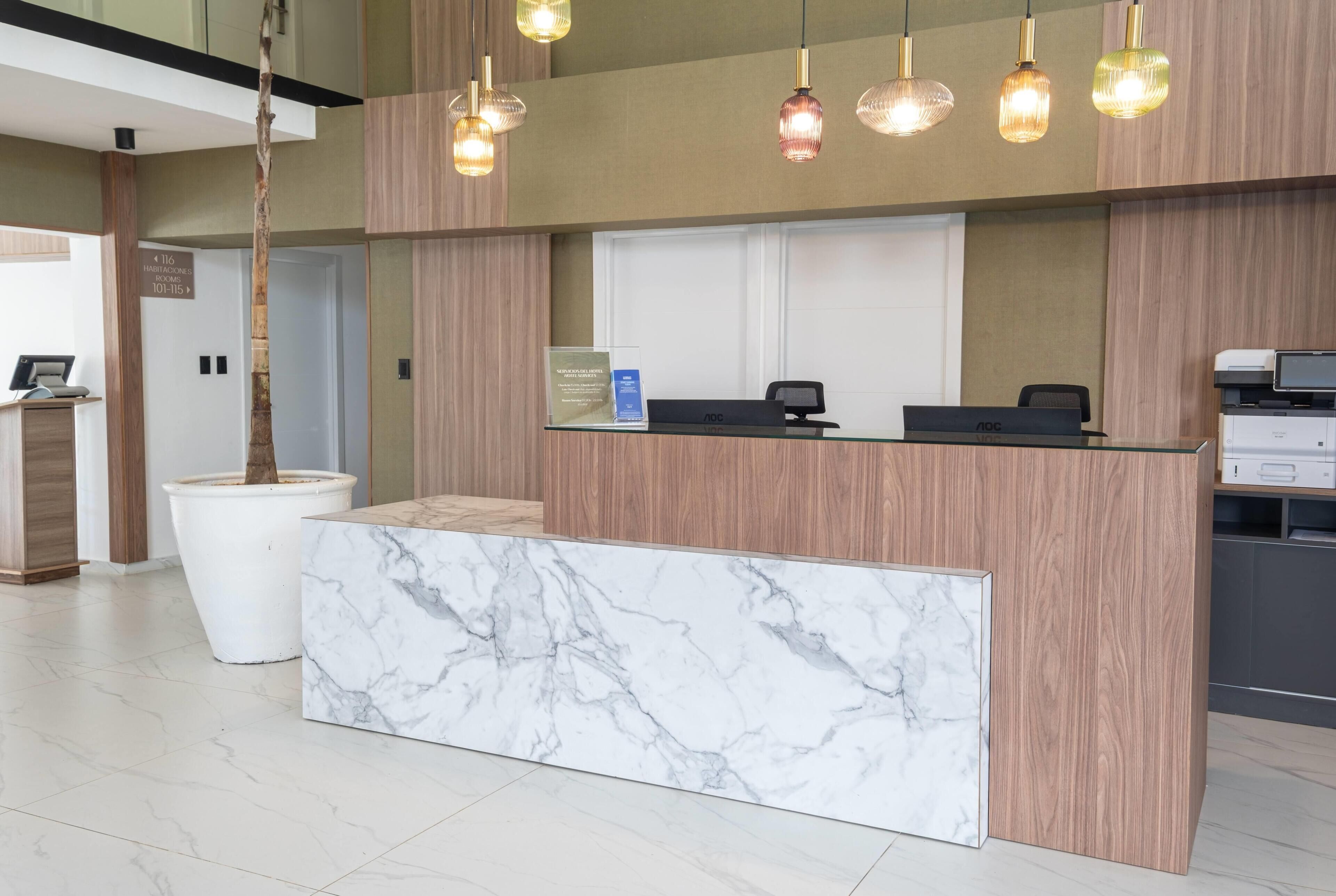 A reception desk with a marble top, wooden paneling, and pendant lighting.