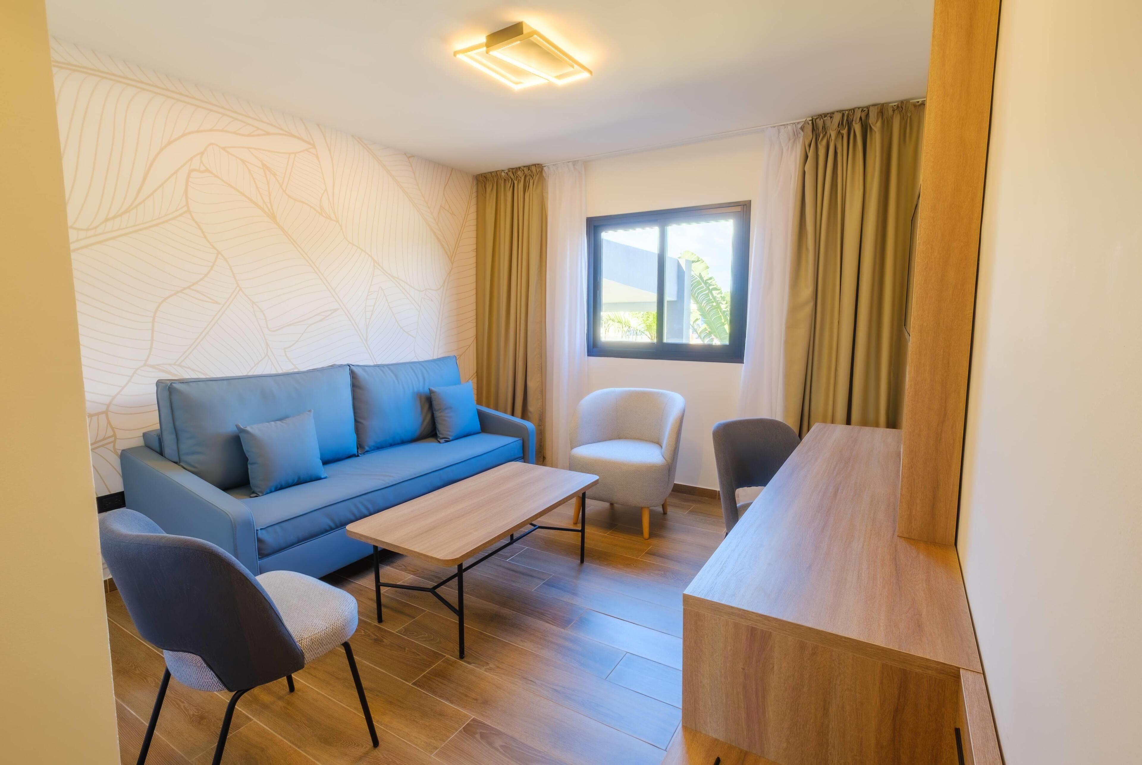 A modern living room with a blue sofa, a wooden coffee table, and two chairs.