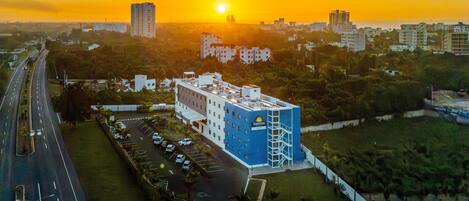 A Days Inn hotel with a parking lot, surrounded by greenery and urban buildings.
