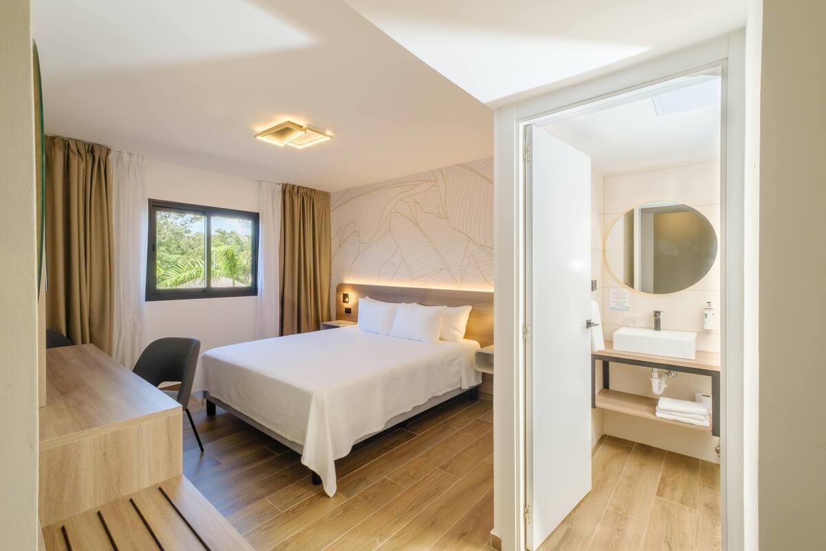 A hotel room with a bed, desk, and bathroom.