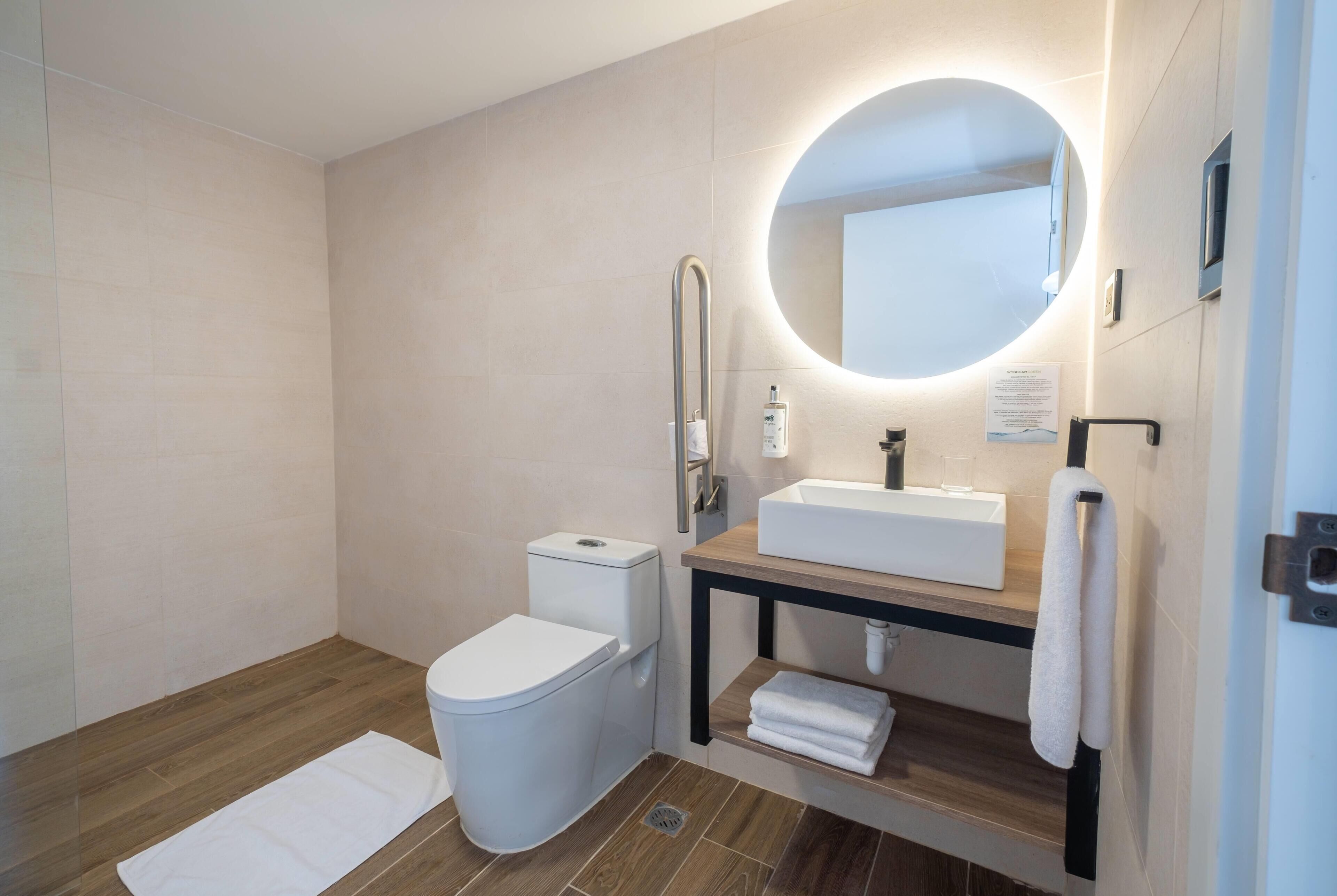 A modern bathroom with a toilet, sink, and mirror.