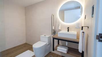 A modern bathroom with a toilet, sink, and mirror.