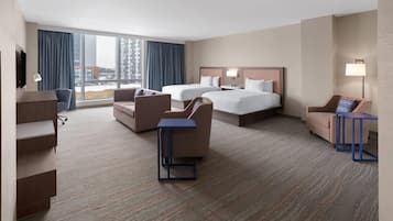 Une chambre d’hôtel avec deux lits, un bureau, une chaise et un téléviseur.