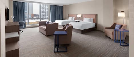 A hotel room with two beds, a desk, a chair, and a TV.