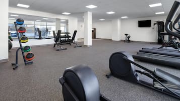 A gym with treadmills, weight machines, and a rack of colorful medicine balls.
