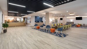 A spacious lobby with a reception desk, seating area, and a cityscape view. - La Quinta Inn & Suites By Wyndham Queens NYC/JFK AirTrain (Jamaica)