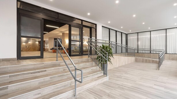 A modern interior with a staircase, wooden flooring, and large windows. - La Quinta Inn & Suites By Wyndham Queens NYC/JFK AirTrain (Jamaica)