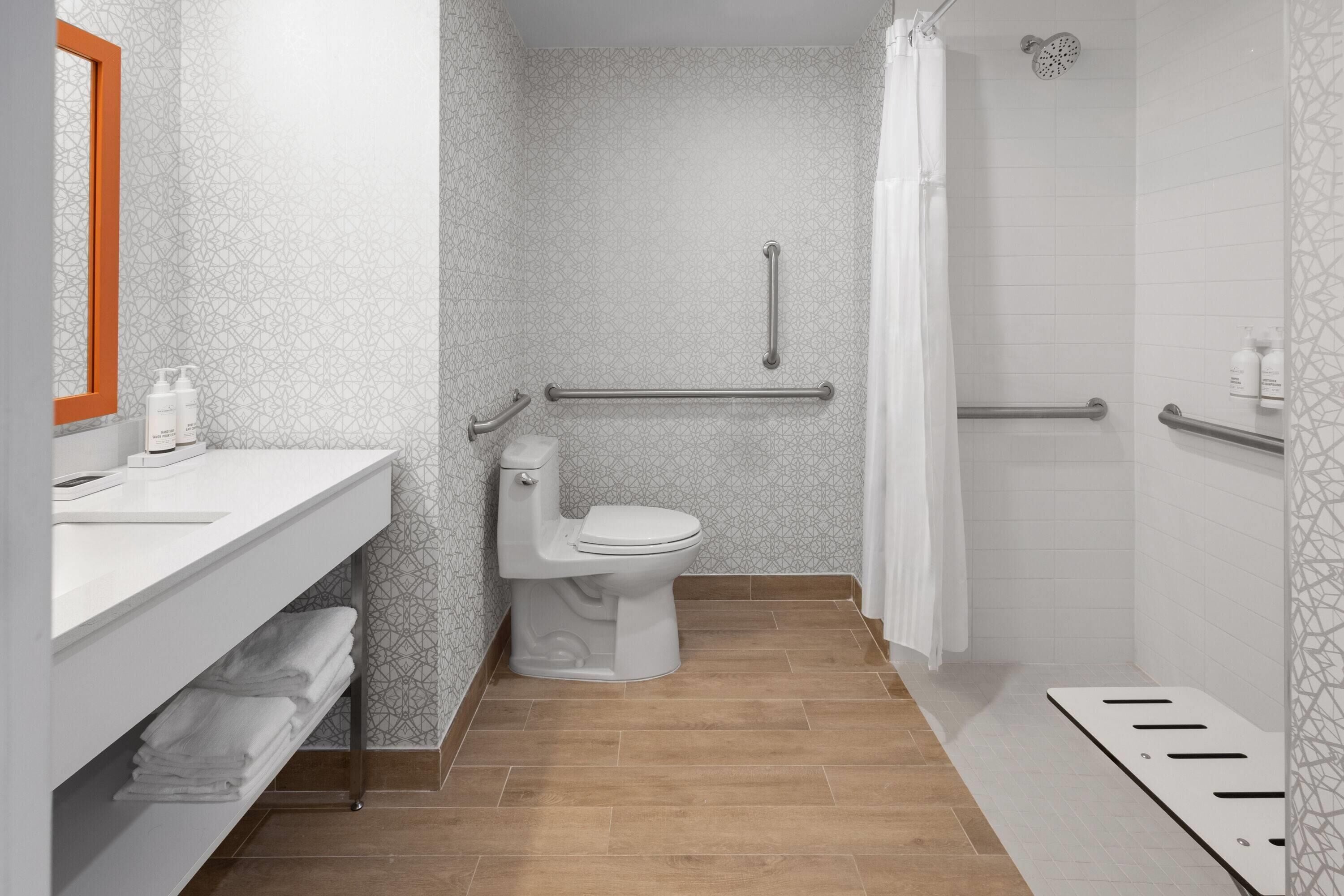 Un baño moderno con inodoro, lavabo con espejo y zona de ducha.