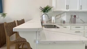 Eine moderne Küche mit weißen Schränken, einer Marmorarbeitsplatte und einer eingebauten Spüle.