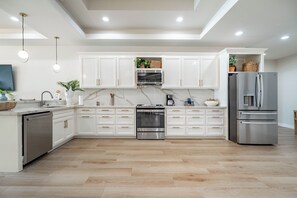 A modern kitchen with white cabinets, stainless steel appliances, and a wooden floor. - Styles Beach 1B - Beach View Condo w/ Pool (San Pedro)