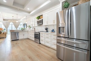 A modern kitchen with stainless steel appliances, white cabinetry, and a wooden floor. - Styles Beach 1B - Beach View Condo w/ Pool (San Pedro)