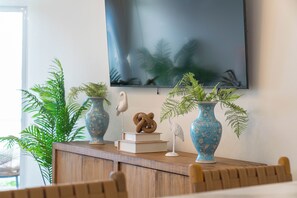 A room with a wooden desk, two blue vases with floral patterns, a white bird sculpture, and a framed picture on the wall. - Styles Beach 1B - Beach View Condo w/ Pool (San Pedro)