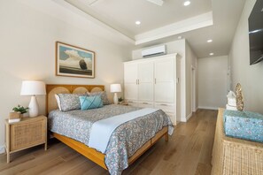Un dormitorio con cama, mesitas de noche, un cuadro, armario y unidad de aire acondicionado.