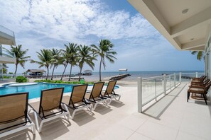 Zona de piscina con sillones de descanso, vista a la playa y cielo despejado.