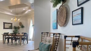 Una sala de estar moderna con comedor, que presenta un sofá de ratán, una mesa de centro redonda y una mesa de comedor con sillas.