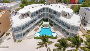Un hotel moderno con piscina central, varios balcones y vistas del entorno.