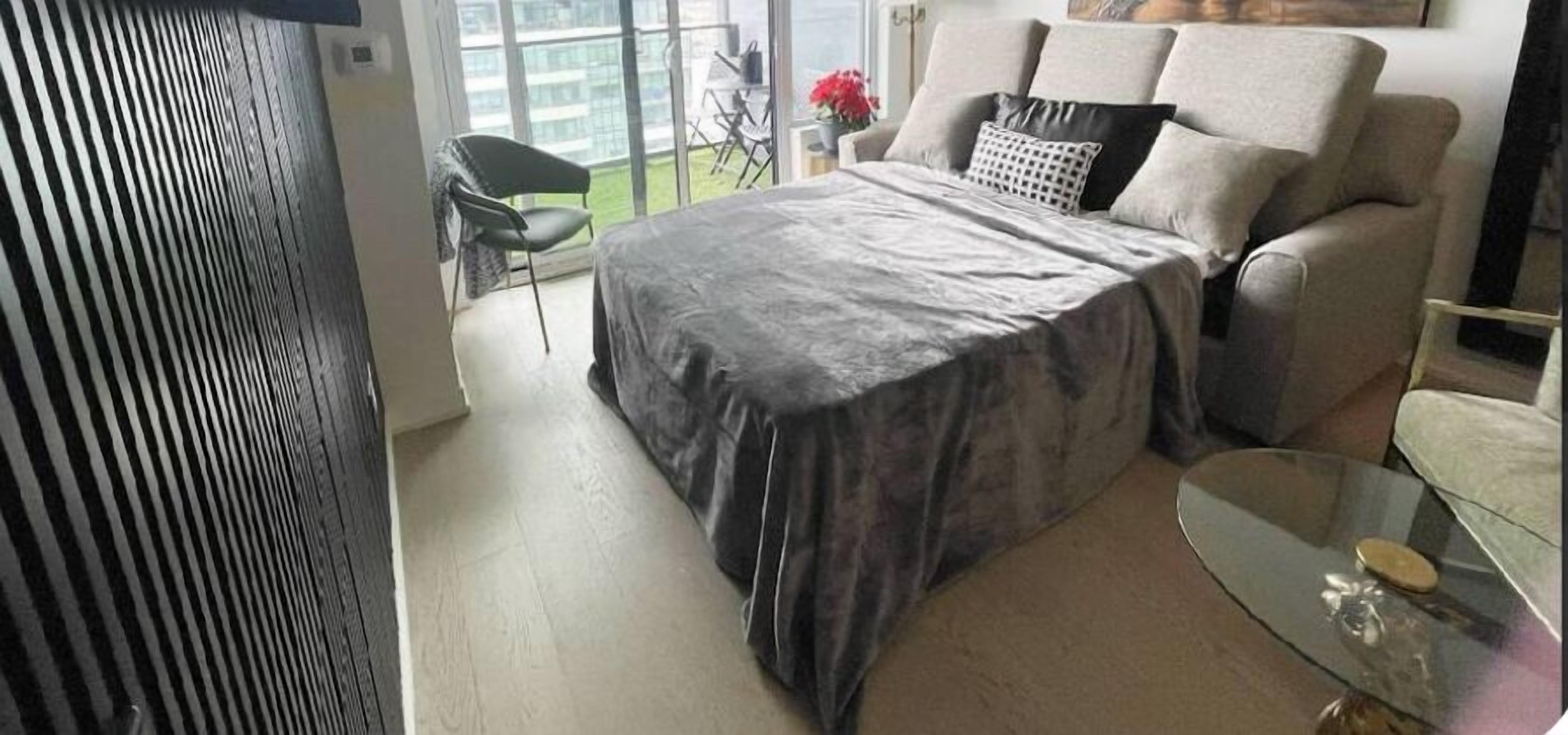 Un dormitorio con una cama, una mesita de vidrio y una silla.