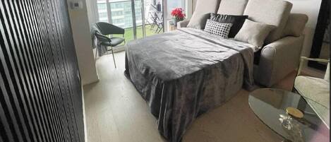 Un dormitorio con una cama, una mesita de vidrio y una silla.
