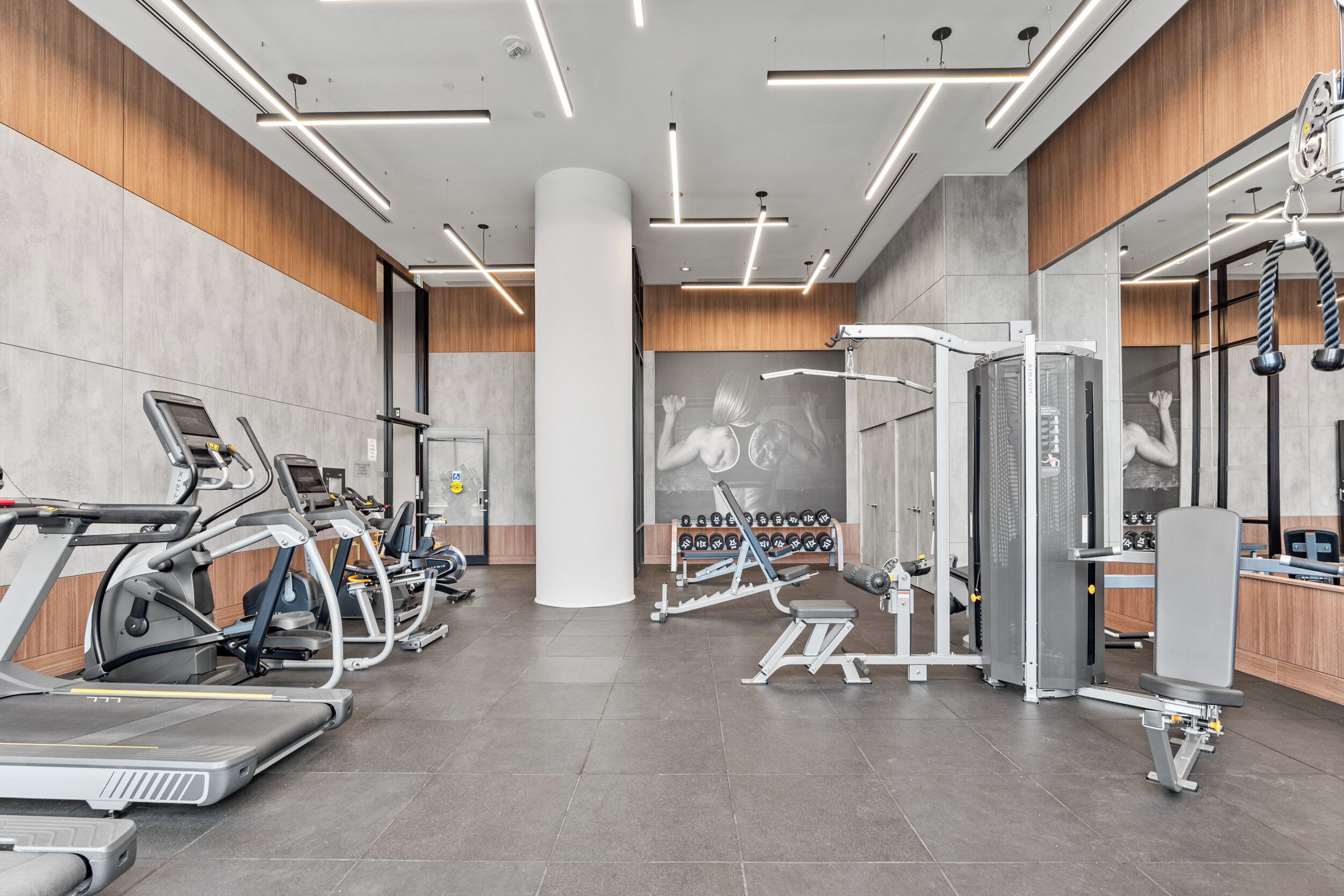 A modern gym with treadmills, weight machines, and a mirrored wall.