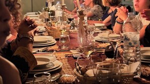 A long table set for a meal in a tented area with candles, plates, glasses, and a bottle of water. - Merzouga white camp  (Merzouga)