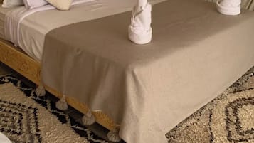 Ett sovrum med en stoppad sänggavel, en stor säng med vita och beige sängkläder och ett element på väggen.