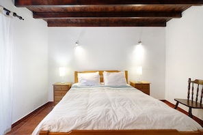 Ein Schlafzimmer mit einem hölzernen Bett, zwei Nachttischlampen, einem Holzstuhl und einem Nachttisch.