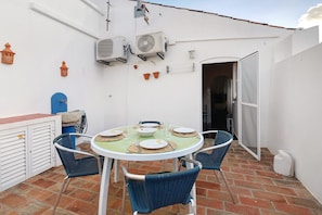 Eine Terrasse mit rundem Tisch, blauen Stühlen und Wandklimaanlagen.