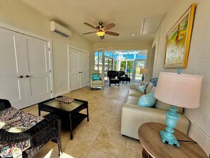 A spacious living room with a ceiling fan, a sofa, a coffee table, and a dining area with chairs. - Bayfront Home on Longboat Key w/Boat Lift (Longboat Key)