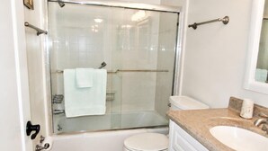 A bathroom with a glass-enclosed shower, a white toilet, and a sink with a granite countertop. - Beachfront Vacation Rental With Full Gulf View (Longboat Key)