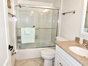A bathroom with a glass-enclosed shower, a white toilet, and a sink with a granite countertop. - Beachfront Vacation Rental With Full Gulf View (Longboat Key)