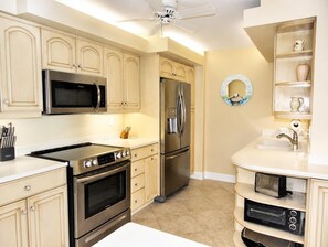 Une cuisine moderne dotée d’appareils électroménagers en acier inoxydable, de meubles de couleur beige et d’un four encastré.