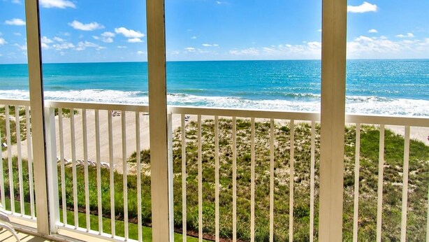 A view from a balcony overlooking a beach with the ocean and a grassy area. - Beachfront Vacation Rental With Full Gulf View (Longboat Key)