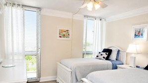 A bedroom with two beds, a ceiling fan, and a window with blinds. - Beachfront Vacation Rental With Full Gulf View (Longboat Key)